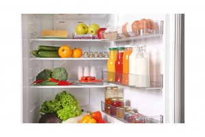An appliance stocked with veggies and condiments that has been arranged using fridge organization tips